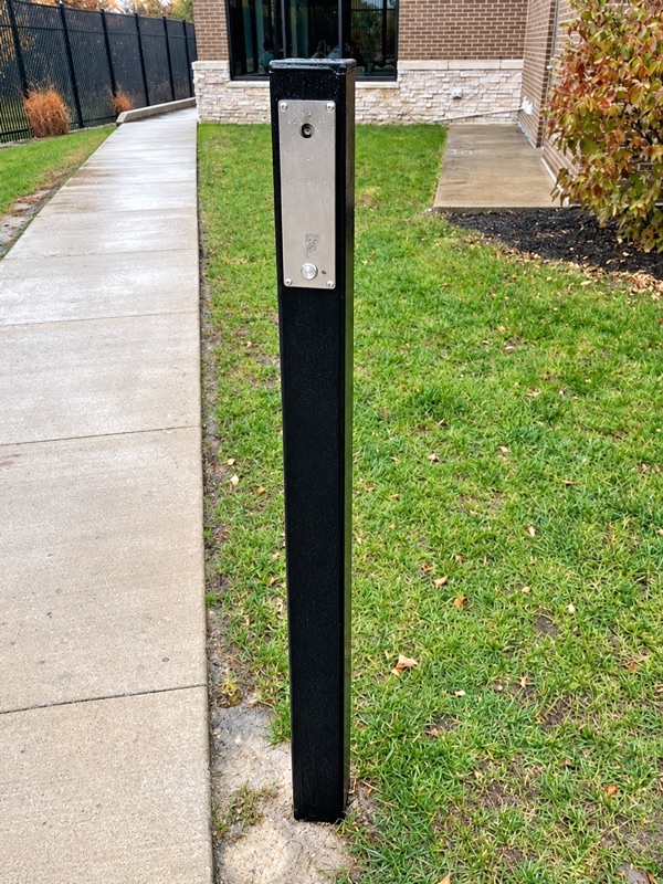 Ozilite cigarette lighter installed in a black outdoor post beside a paved path